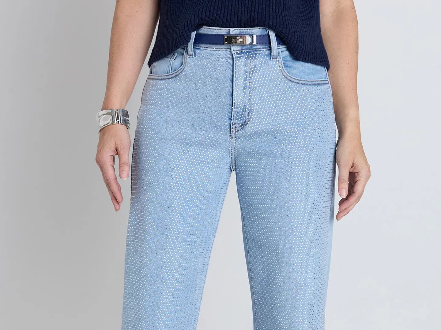 Light-wash high-rise jeans with all-over crystal embellishment, styled with a navy knit.