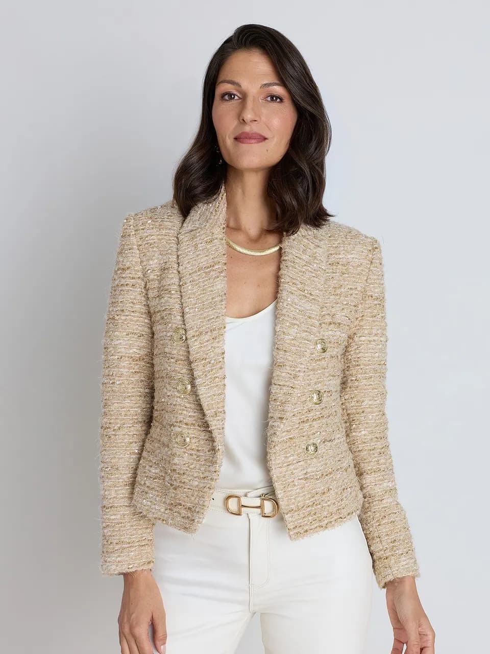 A cropped gold-and-cream tweed blazer worn open over a white cami.