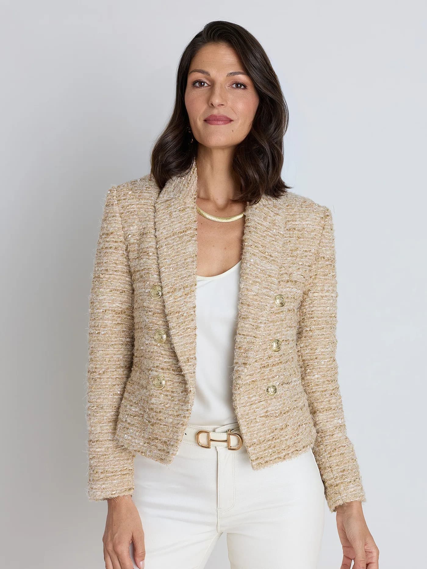A Noli gold-and-cream tweed jacket styled over white trousers.