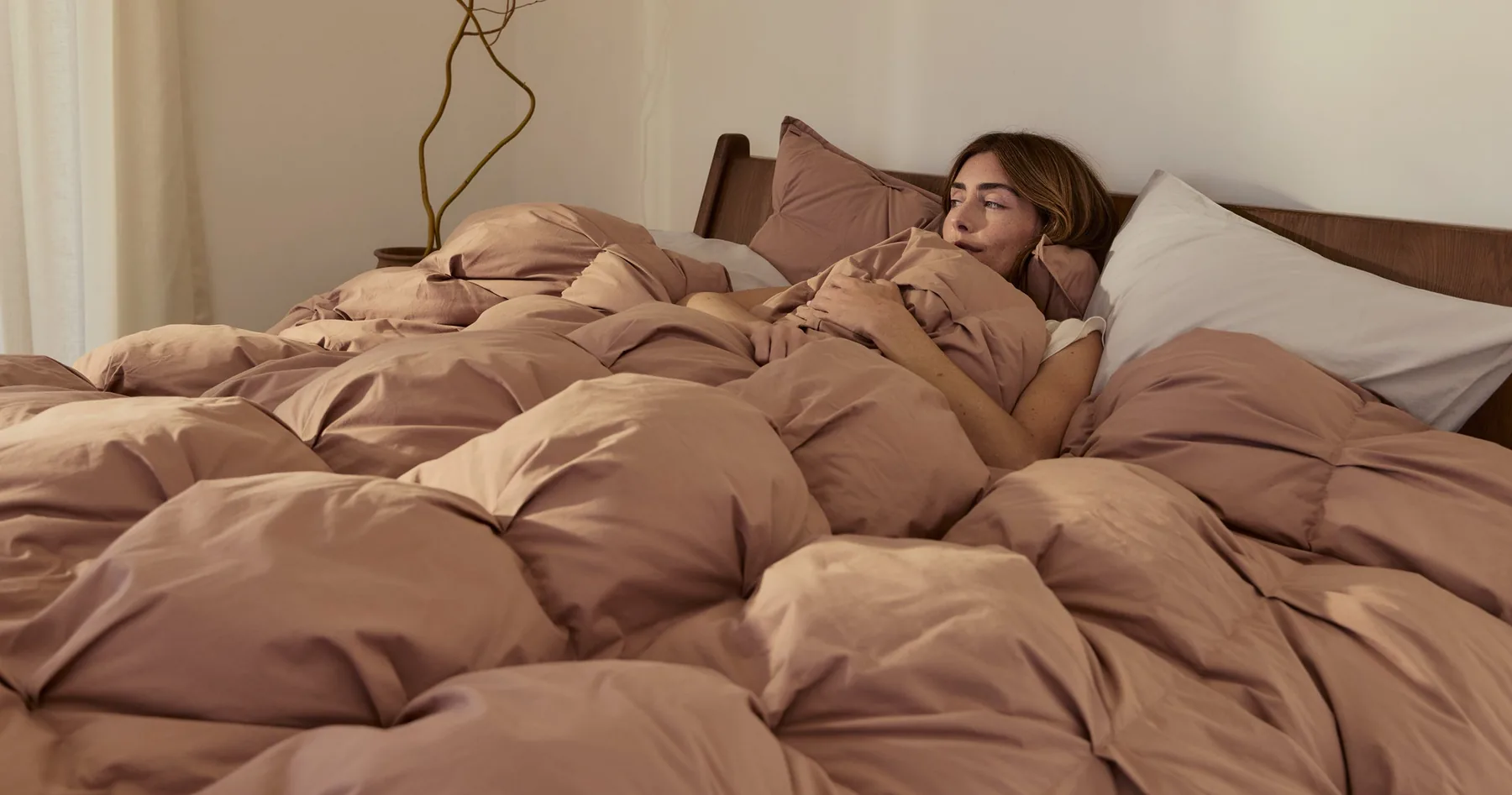A Parachute duvet in clay brown on a made bed, photographed in morning light.