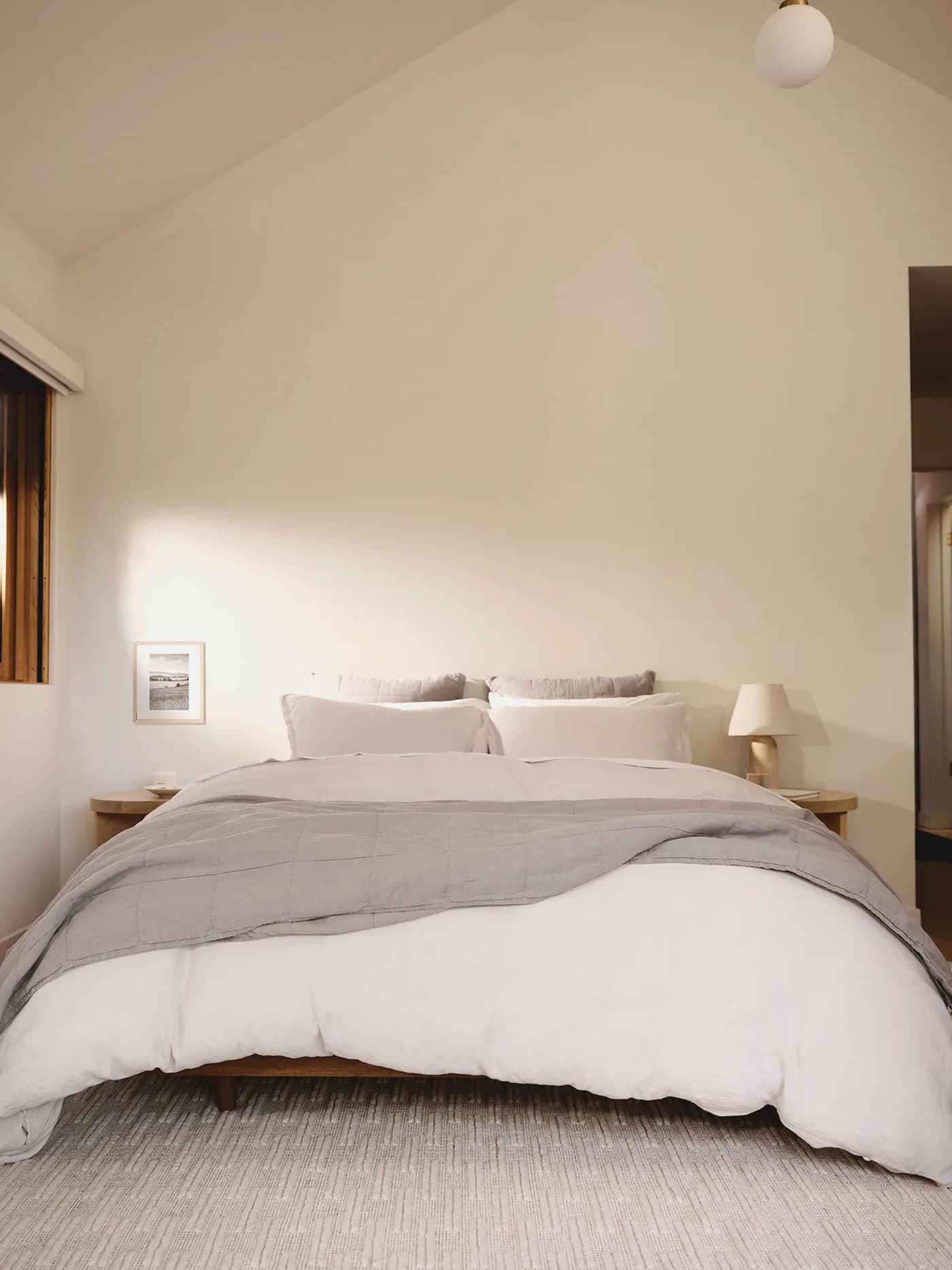 A Parachute bedroom in white and bone linen under a pitched ceiling.