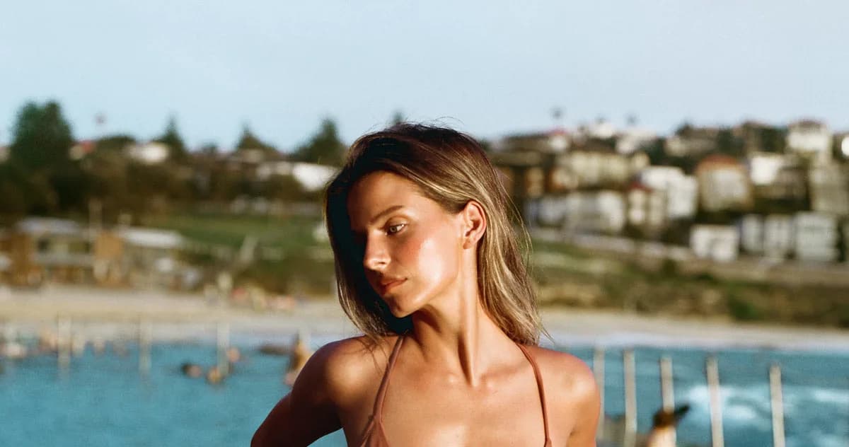 A Tropic of C swim look photographed against a coastal bay in late afternoon light.